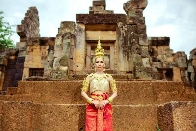 A woman in traditional Cambodian clothing poses at an ancient temple, showcasing cultural heritage.