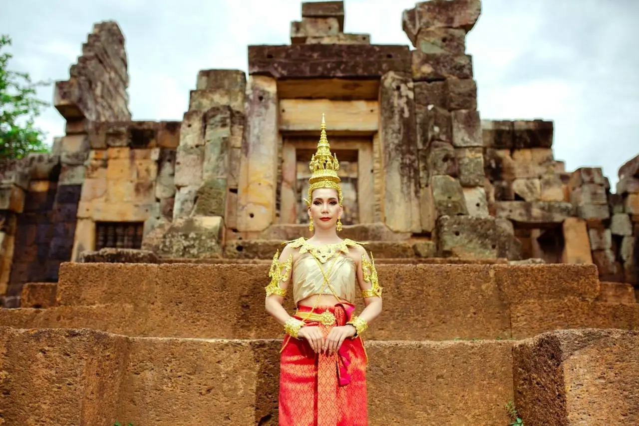 A woman in traditional Cambodian clothing poses at an ancient temple, showcasing cultural heritage.