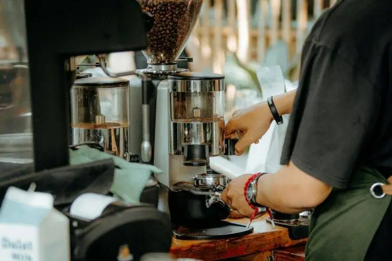 Barista using a coffee grinder to prepare espresso in a modern cafe setting.