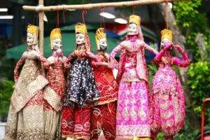 Vibrant display of traditional Rajasthani puppets hanging outdoors.