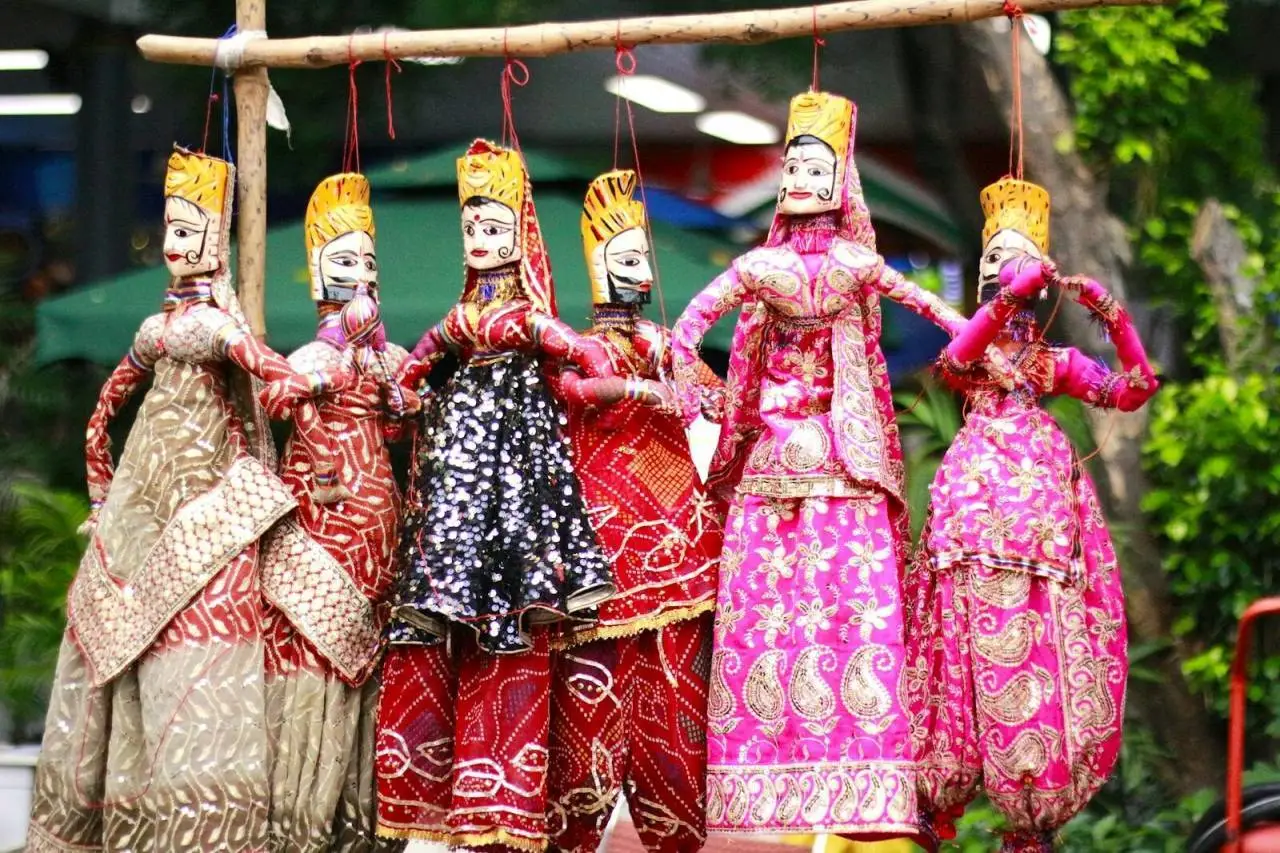 Vibrant display of traditional Rajasthani puppets hanging outdoors.