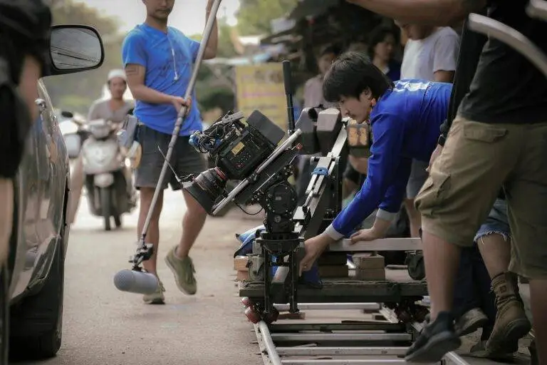 Film crew setting up camera equipment on a street in Thailand, showcasing teamwork and filmmaking techniques.