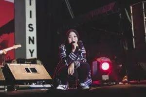 A female singer in a hijab performing on stage during a night concert in Sibolga, Indonesia.